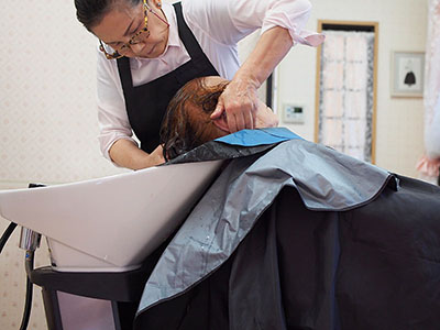 施設のシャンプー台で丁寧に洗髪するスタッフ